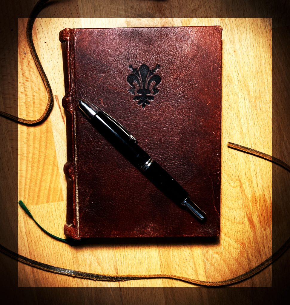 Photo of leather-bound book and pen.